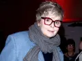 Karolina Korwin Piotrowska w okularach i niebieskim płaszczu, z szarym szalem na szyi.