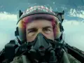 Tom Cruise jako Maverick w hełmie z napisem "MAVERICK" w filmie Top Gun: Maverick. Intensywne spojrzenie pilota w kokpicie myśliwca.