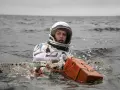 Astronautka w skafandrze z filmu Interstellar 2 w wodzie, z pomarańczowym urządzeniem.
