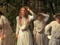 Cztery dziewczyny w białych sukniach szukają czegoś podczas pikniku pod wiszącą skałą.