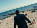 Mężczyzna w garniturze idzie po plaży usianej szczątkami samolotu. Chce zostawić świat za sobą, szukając ratunku.