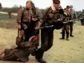 Żołnierz z karabinem ciągnie kobietę za włosy. Obok stoi pies. Idź i patrz, co się dzieje.