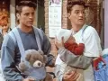 Chandler i Joey z dzieckiem i misiem w nosidełku. Chandler wygląda na lekko zaniepokojonego.
