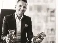 Uśmiechnięty mężczyzna w garniturze trzyma żelki Haribo. Kto gra w reklamie Haribo? To on!