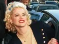 Anna Nicole Smith, z burzą blond loków i czerwoną szminką, wysiada z samochodu.