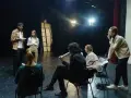 Aktorzy na próbie dyskutują o scenariuszu. Zastanawiają się, ile zarabia reżyser, gdy ich własne pensje są niepewne.