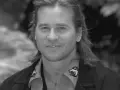 Val Kilmer, znany z wielu filmów, z charakterystycznym uśmiechem i długimi włosami.