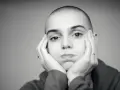 Sinead O'Connor z dłońmi opartymi o policzki, zamyślona.