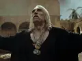 Leo Bonhart, z długimi siwymi włosami i wąsami, w czarnym ubraniu, z kilkoma medalionami na szyi, stoi na deszczu.
