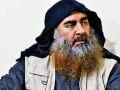 Mężczyzna z długą, siwiejącą brodą i czarnym nakryciem głowy, przypominający Abu Bakra al-Baghdadiego, siedzi w jasnym ubraniu.