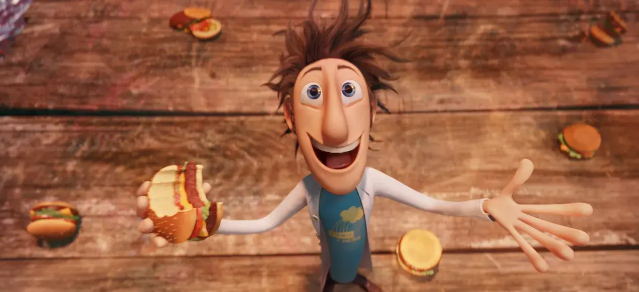 Flint Lockwood trzyma nadgryzionego hamburgera, podczas gdy wokół niego spadają klopsiki i inne zjawiska pogodowe.