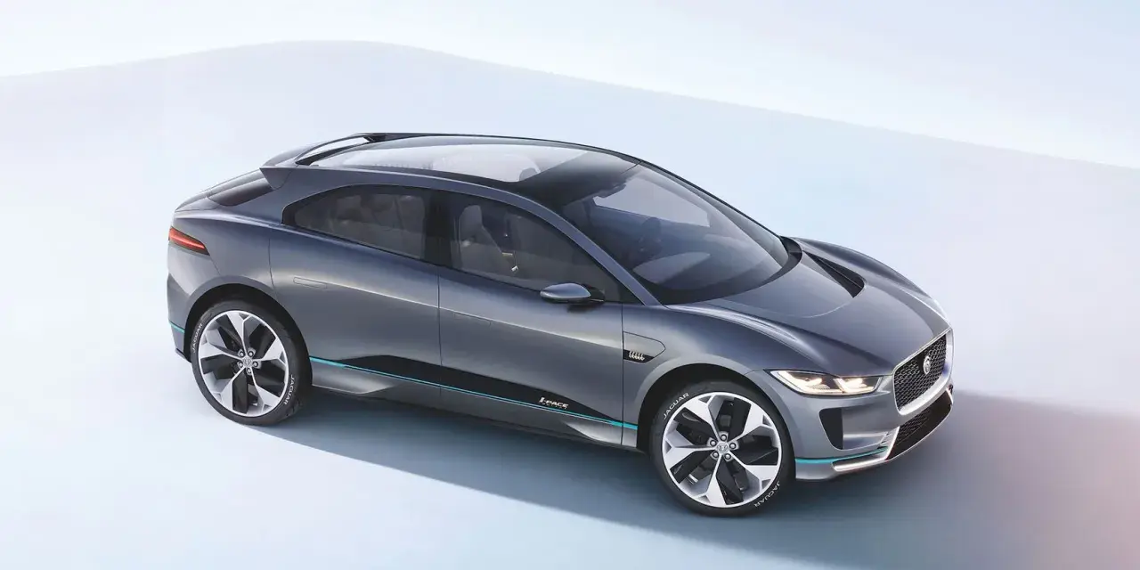 Elegancki, szary Jaguar I-PACE, niczym czarny jaguar gotowy do skoku, prezentuje swoją aerodynamiczną sylwetkę na jasnym tle.