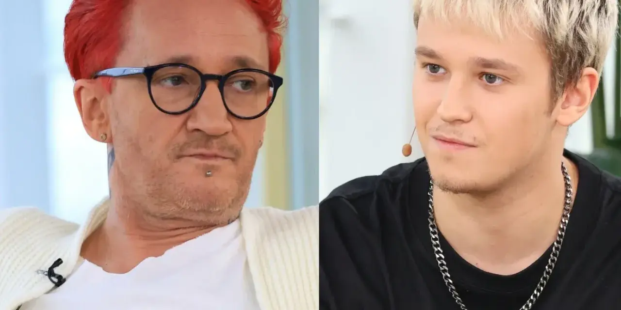 Xavier Michał Wiśniewski z charakterystycznymi rudymi włosami i okularami obok młodszego mężczyzny z blond fryzurą.