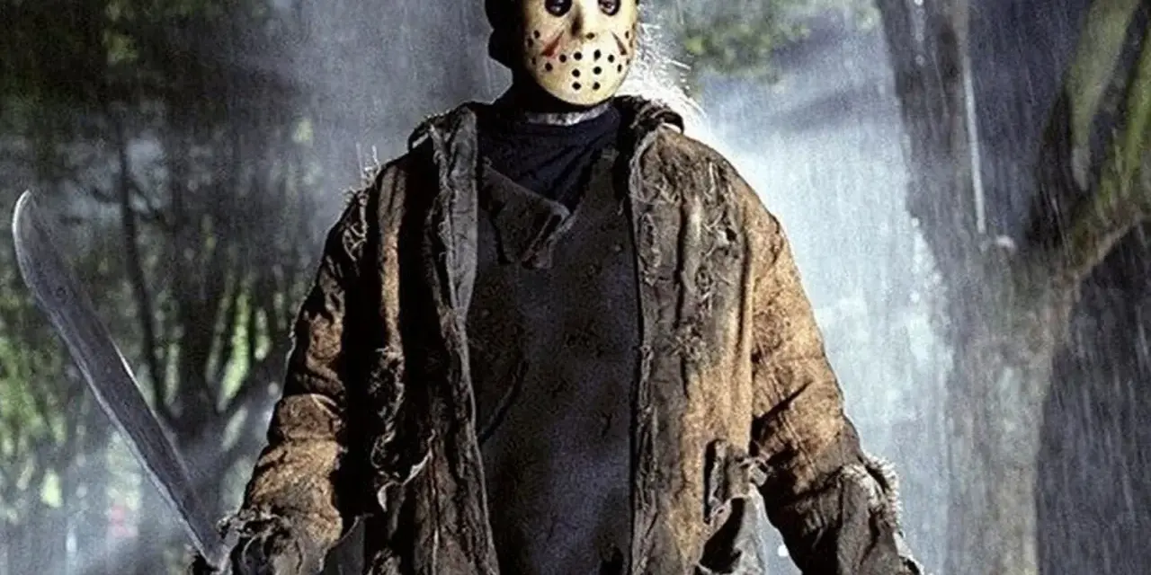 Jason Voorhees, ikona horrorów, w swojej zniszczonej kurtce i z maczetą, stoi w deszczu.