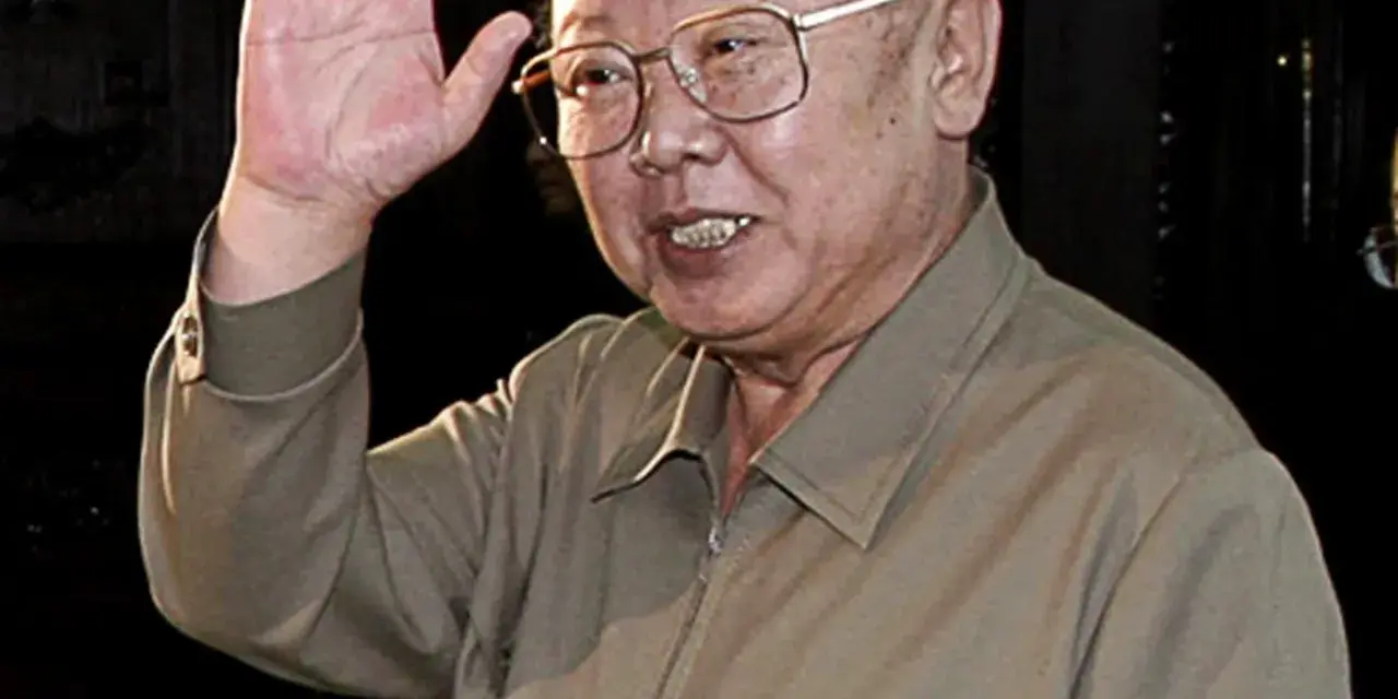 Kim Jong Il w okularach, machający ręką.