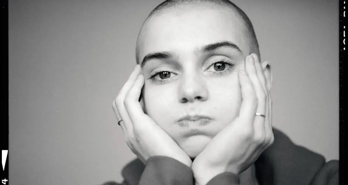 Sinead O'Connor z dłońmi opartymi o policzki, zamyślona.