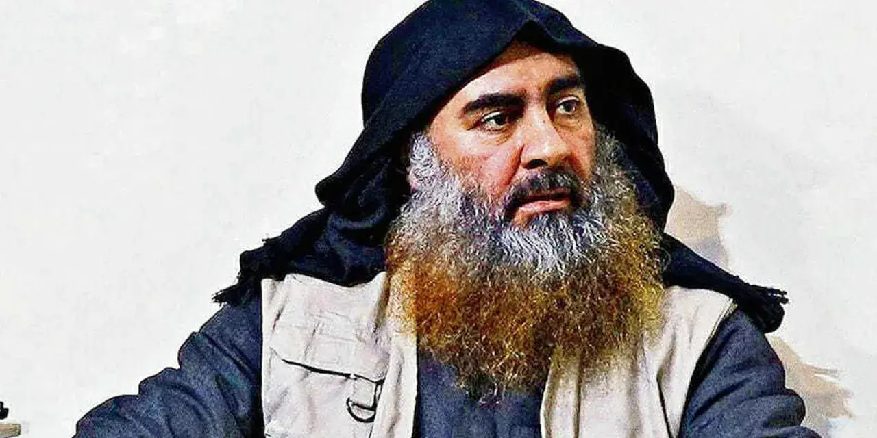 Mężczyzna z długą, siwiejącą brodą i czarnym nakryciem głowy, przypominający Abu Bakra al-Baghdadiego, siedzi w jasnym ubraniu.