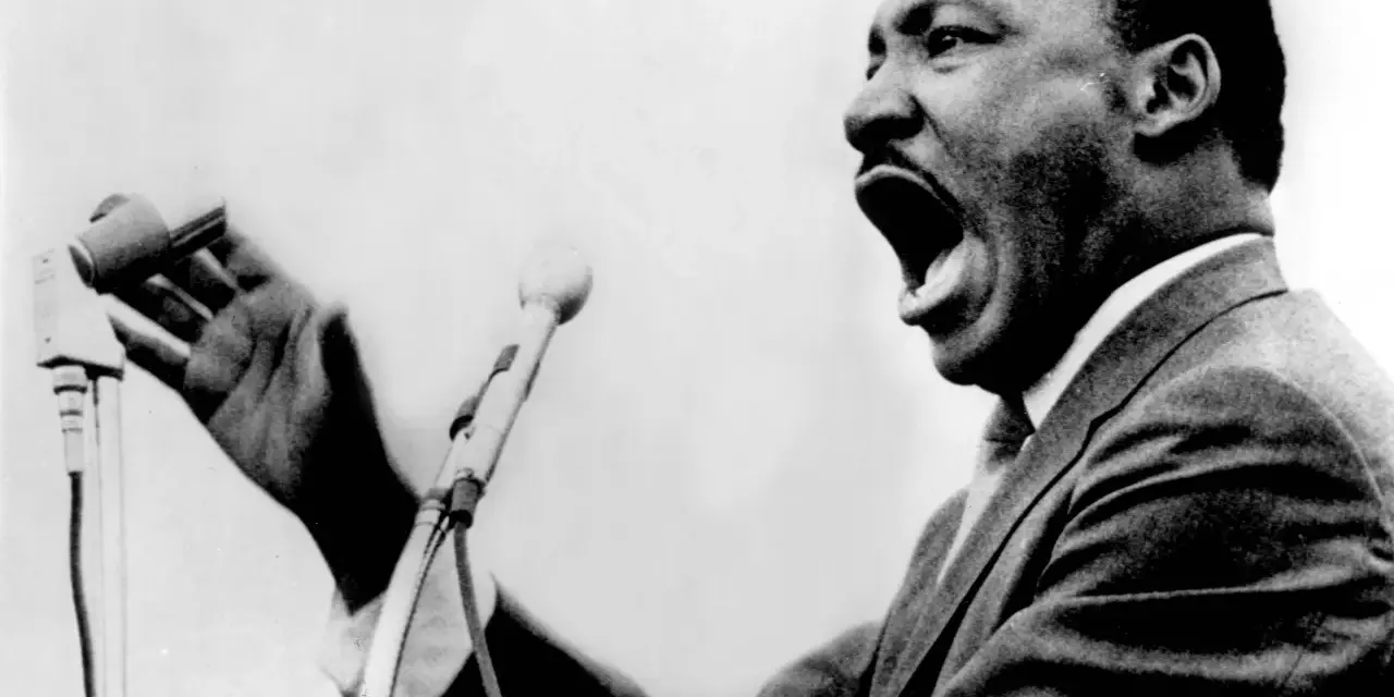 Martin Luther King przemawia z pasją do mikrofonu, jego głos niesie nadzieję i wolność.