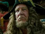 Kapitan Barbarossa w pirackim kapeluszu, z burzą loków i brodą, spogląda w dal. Obok niego inny pirat w czerwonym stroju.