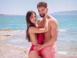 Para z "Love Never Lies Sezon 4" na plaży, w objęciach, z morzem w tle.
