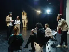 Aktorzy na próbie dyskutują o scenariuszu. Zastanawiają się, ile zarabia reżyser, gdy ich własne pensje są niepewne.