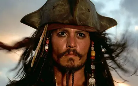 Kapitan Jack Sparrow w swoim charakterystycznym kapeluszu i z koralikami we włosach, gotowy na kolejną morską przygodę.