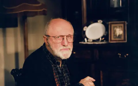 Portret starszego mężczyzny z siwą brodą i okularami. W tle widać meble i ozdobną zastawę. Wiele osób zastanawia się, jak zmarł Henryk Machalica.