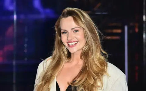 Uśmiechnięta Żaneta Rosińska, której wiek dodaje jej uroku, w białej marynarce i czarnej kreacji.