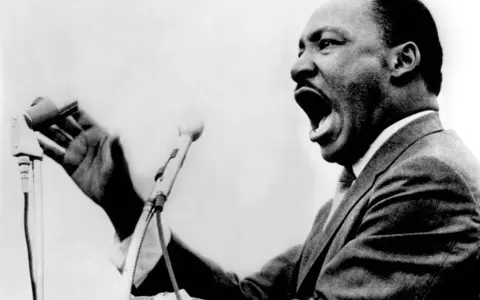 Martin Luther King przemawia z pasją do mikrofonu, jego głos niesie nadzieję i wolność.
