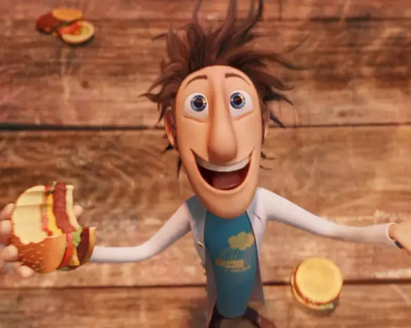 Flint Lockwood trzyma nadgryzionego hamburgera, podczas gdy wokół niego spadają klopsiki i inne zjawiska pogodowe.
