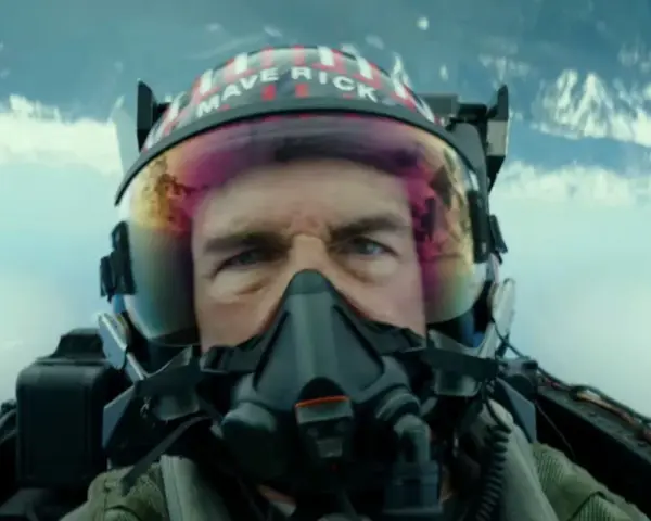 Tom Cruise jako Maverick w hełmie z napisem "MAVERICK" w filmie Top Gun: Maverick. Intensywne spojrzenie pilota w kokpicie myśliwca.