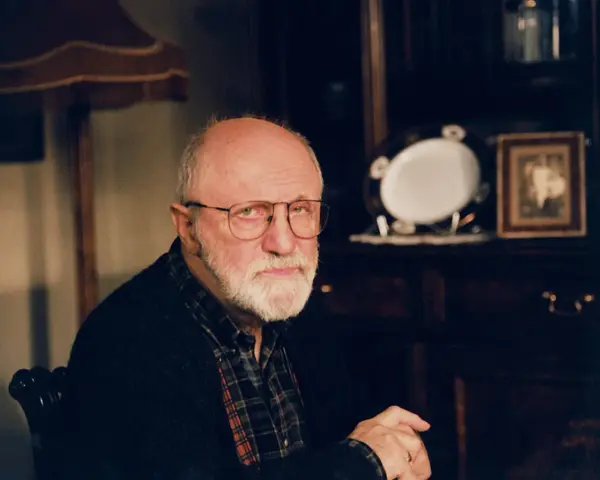 Portret starszego mężczyzny z siwą brodą i okularami. W tle widać meble i ozdobną zastawę. Wiele osób zastanawia się, jak zmarł Henryk Machalica.