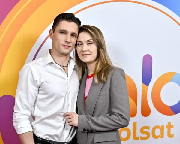 Małgorzata Patryn Gurłacz z partnerem pozują na tle kolorowego logo.