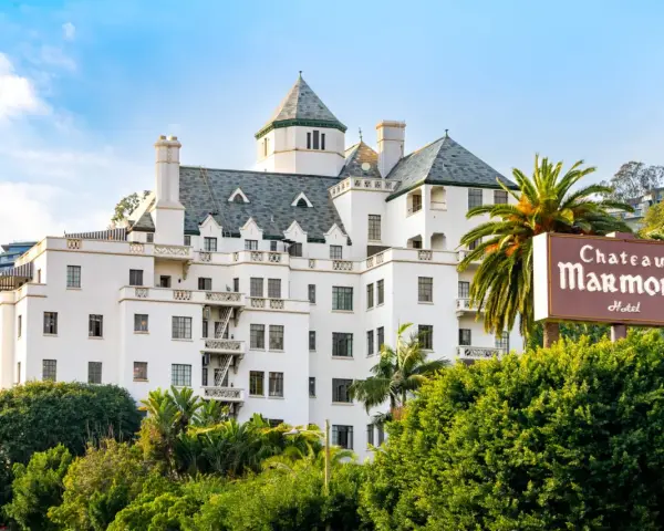 Chateau Marmont, miejsce, gdzie może mieszkać Keanu Reeves, to biały hotel z zielonym dachem i palmami.