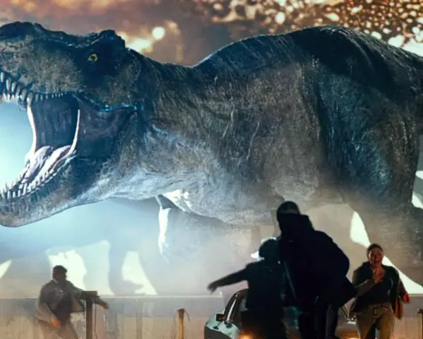 Gigantyczny Tyranozaur Rex z Jurassic World 3 z otwartą paszczą ściga ludzi wśród samochodów.