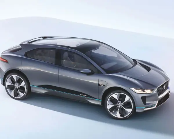 Elegancki, szary Jaguar I-PACE, niczym czarny jaguar gotowy do skoku, prezentuje swoją aerodynamiczną sylwetkę na jasnym tle.