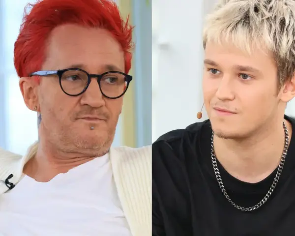 Xavier Michał Wiśniewski z charakterystycznymi rudymi włosami i okularami obok młodszego mężczyzny z blond fryzurą.