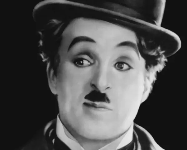 Charlie Chaplin w meloniku, z charakterystycznym wąsikiem, jakby opowiadał historie dla dzieci.