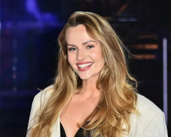 Uśmiechnięta Żaneta Rosińska, której wiek dodaje jej uroku, w białej marynarce i czarnej kreacji.