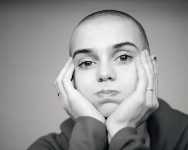 Sinead O'Connor z dłońmi opartymi o policzki, zamyślona.