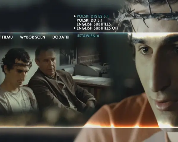 Mężczyzna z koroną cierniową na głowie, jakby wszyscy jesteśmy chrystusami, siedzi obok starszego mężczyzny. Menu filmu wyświetla opcje.