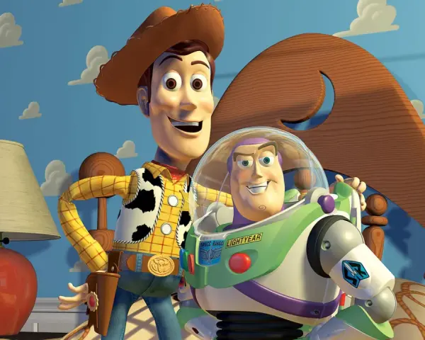 Woody i Buzz Lightyear, bohaterowie bajek z dzieciństwa, pozują na tle niebieskiej ściany z chmurkami.