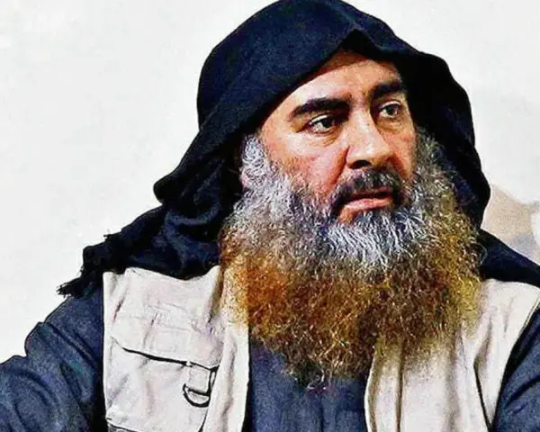 Mężczyzna z długą, siwiejącą brodą i czarnym nakryciem głowy, przypominający Abu Bakra al-Baghdadiego, siedzi w jasnym ubraniu.