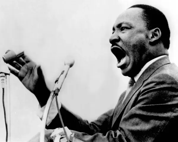 Martin Luther King przemawia z pasją do mikrofonu, jego głos niesie nadzieję i wolność.