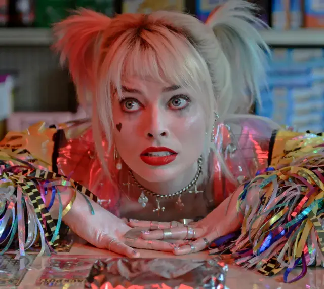 Harley Quinn z filmu "Ptaki Nocy" z błyszczącymi wstążkami i makijażem.