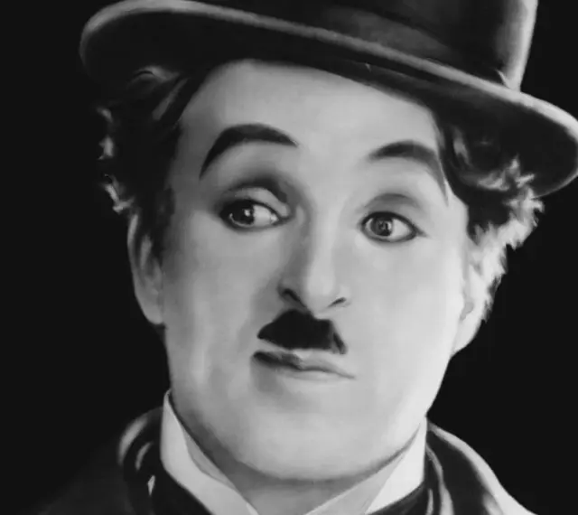 Charlie Chaplin w meloniku, z charakterystycznym wąsikiem, jakby opowiadał historie dla dzieci.