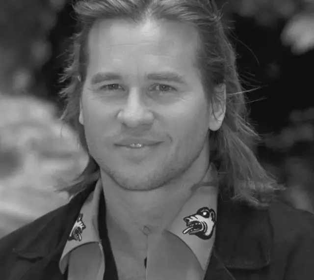 Val Kilmer, znany z wielu filmów, z charakterystycznym uśmiechem i długimi włosami.