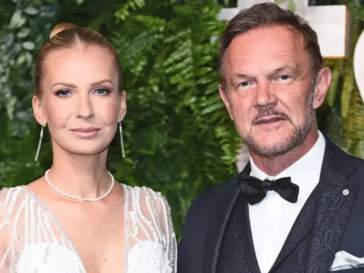 Cezary Pazura z żoną Edytą na ściance. Ona w białej, zdobionej sukni, on w eleganckim garniturze.