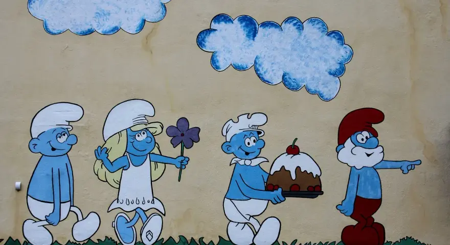 Smerfy z imionami: Papa Smerf wskazuje drogę, a kucharz niesie tort. Obok Smerfetka z kwiatkiem.