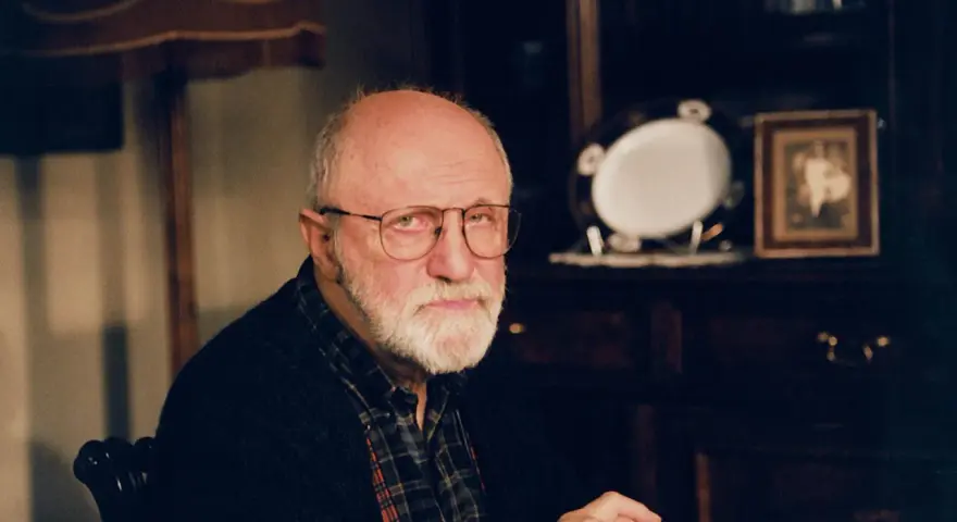 Portret starszego mężczyzny z siwą brodą i okularami. W tle widać meble i ozdobną zastawę. Wiele osób zastanawia się, jak zmarł Henryk Machalica.